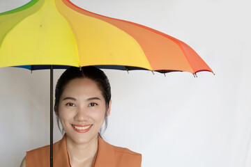 Happy smiling Asian beautiful woman  under rainbow colored umbrella with positive smile