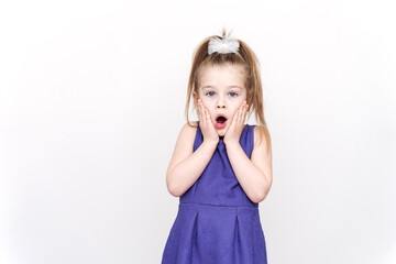 emotional surprised 5-6 year old girl in a purple dress. hands near the face, wow effect