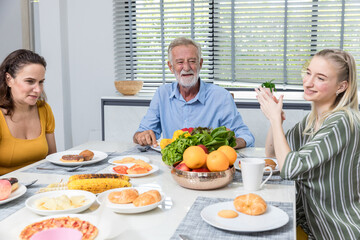 Happy family spend time having lunch or dinner on table together. Senior man enjoying while communicating with their family in dining room. Dad fun with family dinner together.