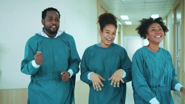 Happy African American nurses and assistants dances while walk through the corridors of hospital. medical personnel having enjoy.