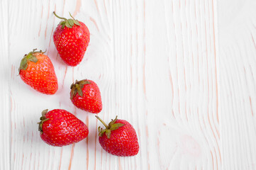 a pile of strawberries close-up on a white wooden background with copy space