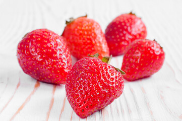a pile of strawberries close-up on a white wooden background