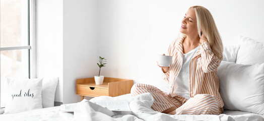 Morning of beautiful mature woman drinking coffee in bedroom