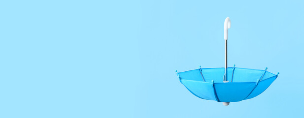 Open umbrella on light blue background with space for text