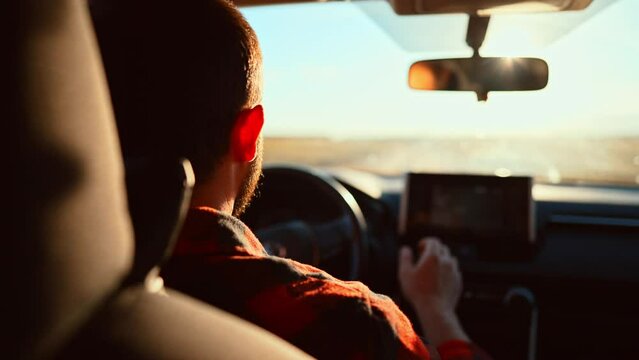 Rear view in saloon auto on male who driving on rural road. Blurred view from front window car and rear view inside mirror. Summer travel by transport outside city on uneven sections bumps and pits.