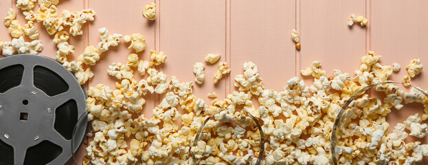 Tasty popcorn with film reel on color wooden background