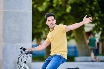 Happy man smiling while enjoying a ride on a bike outdoors. Transport and urban lifestyle concept.