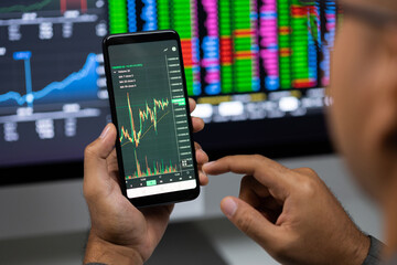 Close-up financial using smartphone analyze exchange rate diagram. Investor businessman analyzing a graphic of stock cryptocurrency exchange chart with cell phone. Investment concept