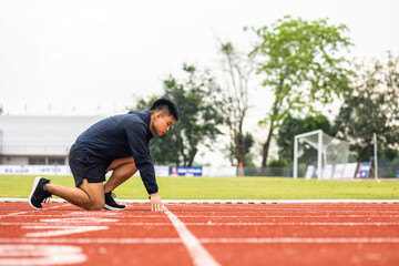 Fototapeta premium Young handsome chinese man doing star pose before running exercise on track in sport stadium. Challenge race of athletes running in the starting point