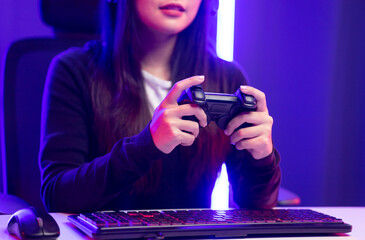 Close up hands Playing video game. Young pretty woman holding joystick controller console. Female Professional Streaming playing game online in dark room neon light. © Chanakon