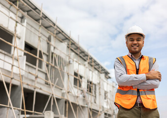 Confident engineer handsome man standing arms crossed at modern home building construction. Architect with white safety helmet at construction site.