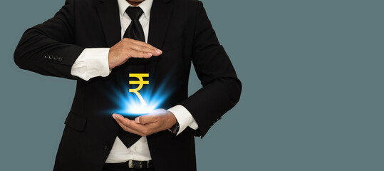 Indian rupee sign between two hands of businessman with copy space for banner.