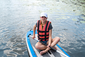 an experienced athlete in a vest rides on the water on a board sap on the lake in weather.