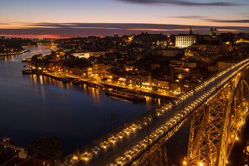 The cityscape of Porto with a bridge in the foreground at sunset and nightfall