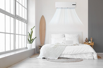 Interior of modern bedroom with operating air conditioner