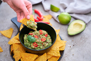 Guacamole dip with tortilla chips or nachos on black serving board