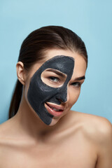 Beautiful young woman with mask for the face of black clay on clean fresh skin . Girl model beauty face care with moisturizer cosmetic mask. Facial treatment . Skin care