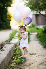 Funny girl child toddler with two tails with balloons outside. Balloons of pastel delicate colors