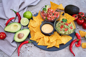 freshly made salsa and guacamole dip sauce with nacho chips on stone serving board