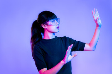 Metaverse concept. Young asian woman in black t-shirt wearing vr classes posing touching on purple...