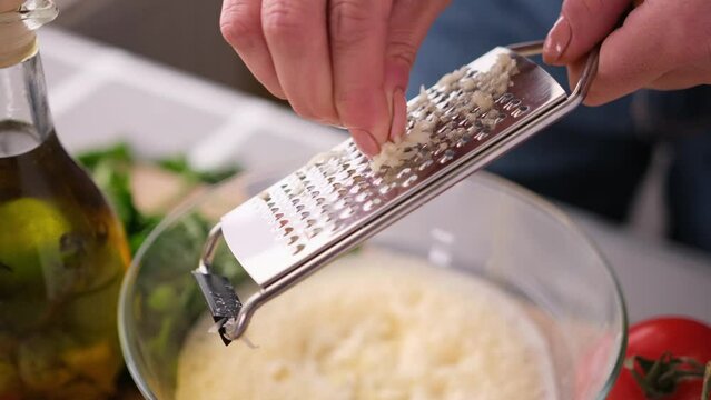 Making Caesar salad sauce - woman adding grated garlic into glass bowl