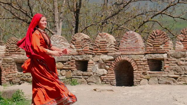A girl in a national Georgian red dress is dancing. Selective focus.