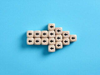 Arrow icon made of wooden cubes with little arrow icons pointing opposite direction. Resistance to change in business