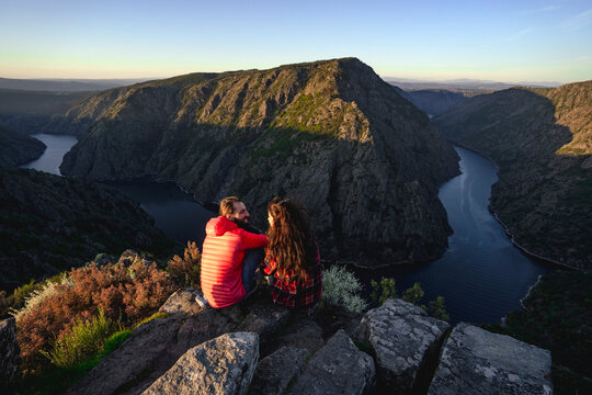 Couple sitting on rocks near Sil river in valley
