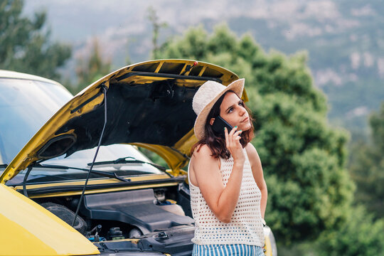 Woman Talking On Mobile Phone In Front Of Broken Down Van