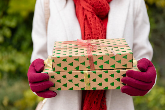 Young woman wearing gloves holding Christmas presents