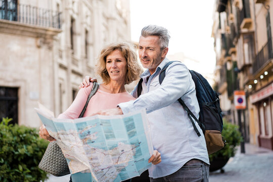 Mature tourists examining map in city on vacation