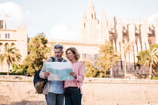 Mature tourists reading map in city