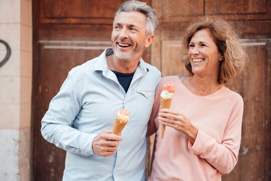 Cheerful Mature Couple With Ice Cream In Front Of Door