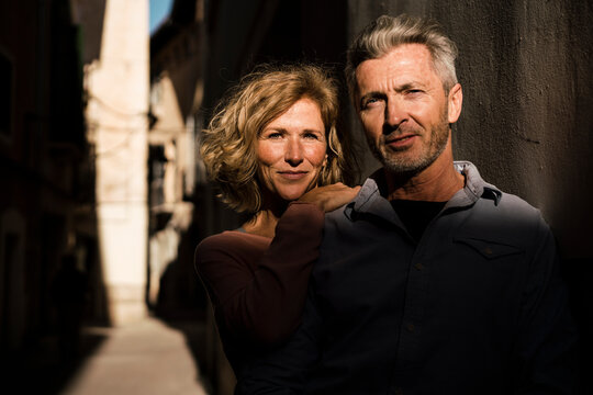 Confident mature couple amidst walls on sunny day