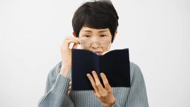 老眼鏡で読書をするミドル女性