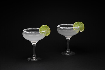 Glasses of tasty margarita cocktail on dark background