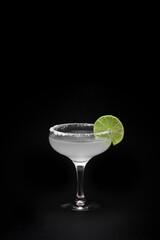 Glass of tasty margarita cocktail on dark background