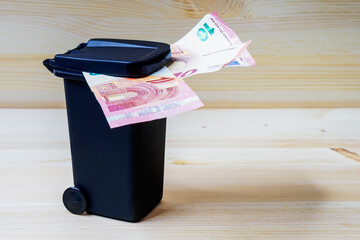 Euro Geldschein in einer Mülltonne als Symbol für Müllgebühren, Geldverschwendung