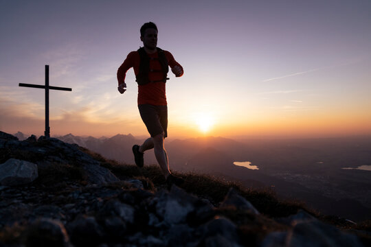 Silhouette man running on top of Sauling mountain at sunset