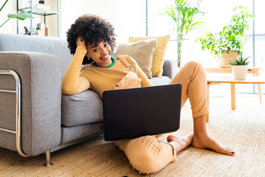 Happy Woman With Laptop Leaning On Sofa At Home