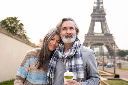 Smiling mature woman with eyes closed leaning on man standing in front of Eiffel tower, Paris, France
