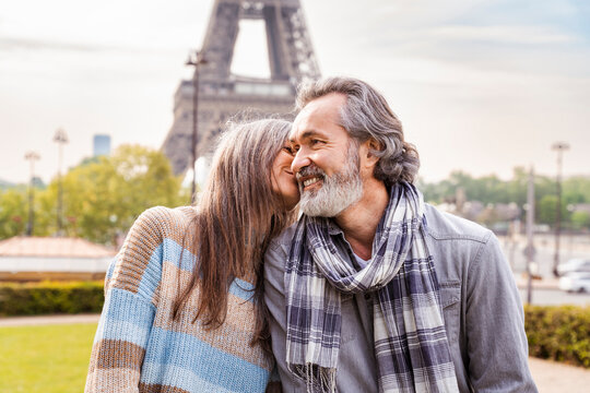 Mature woman kissing boyfriend in front of Eiffel tower, Paris, France