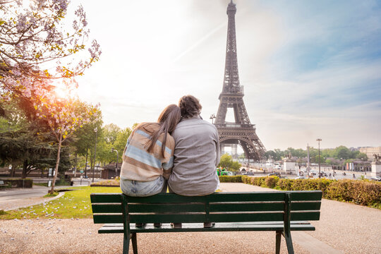 Mature couple sitting together on bench in front of Eiffel tower, Paris, France