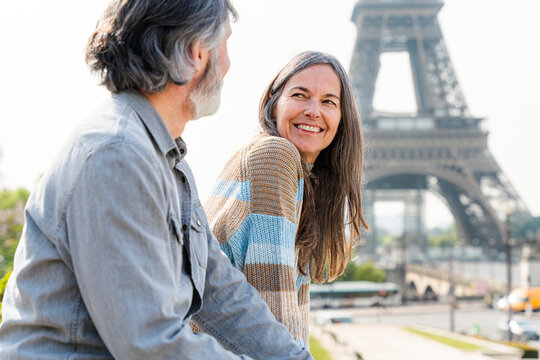 Happy mature woman looking at man sitting in front of Eiffel tower, Paris, France