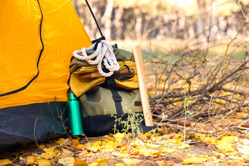 Naklejka premium Tourist's backpack with survival kit near tent in forest