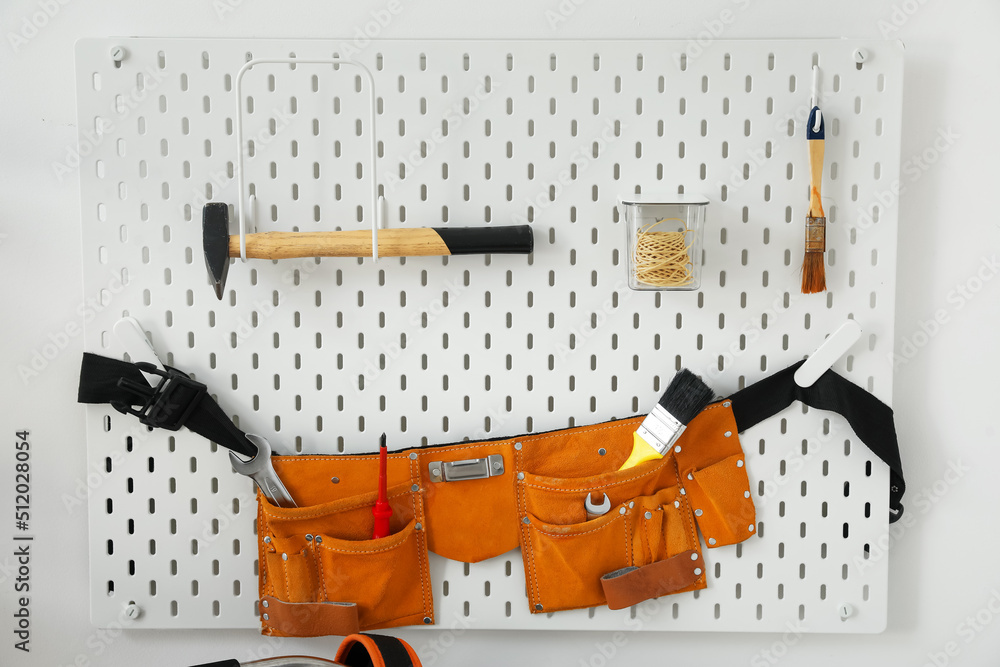 Wall mural Pegboard with belt and different tools on light wall