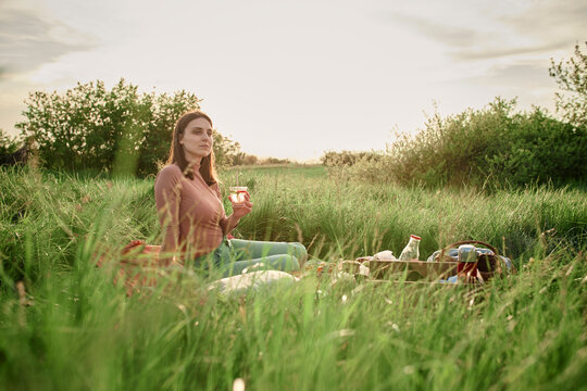 Thoughtful woman having infused water in field on weekend