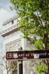 A picture of the Arc de Triomphe behind a street sign  