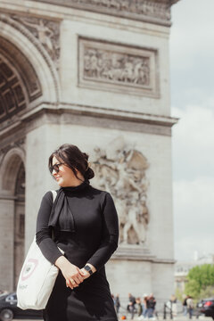 A Woman Standing In Front Of The Arc De Triomphe 