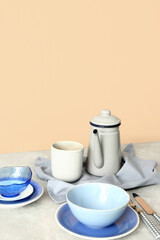 Elegant setting with plates, cup and teapot on grey table against beige background